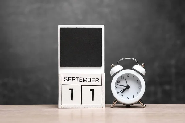 Calendar with september 11 date and alarm clock on table against chalk board background