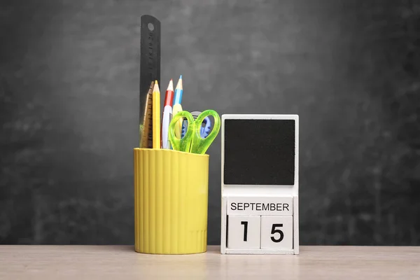 Calendar with september 15 date and school supplies on table against chalk board background