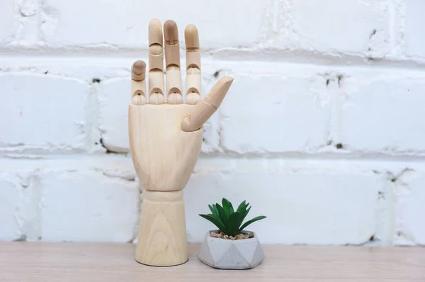 Puppet hand and plant on table against a brick wall. Office decor