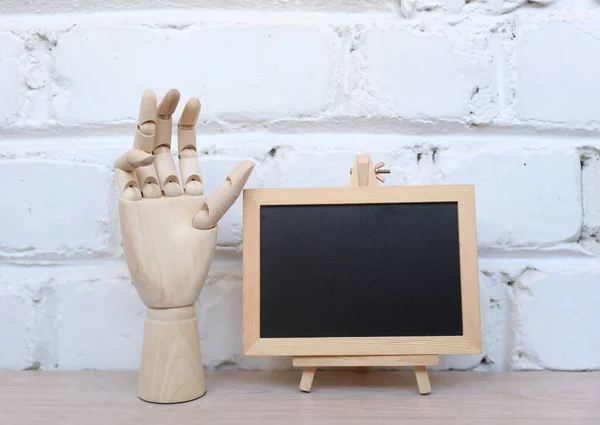 Chalk board with puppet hand on table against brick wall background