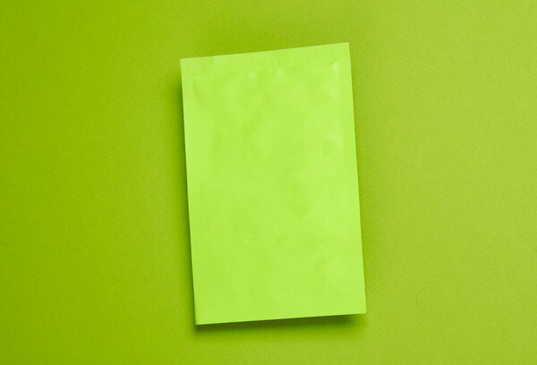 Зеленая плоская пластиковая упаковка на зеленом фоне. Вид сверху