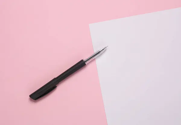 White sheet of paper with a pen on a pink background. Space for text
