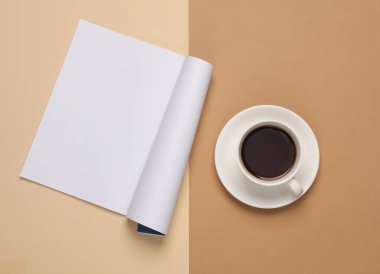 Beyaz boş dergi sayfası modeli ve kahverengi arka planda kahve fincanı. Üst görünüm