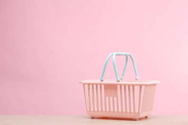 Pembe arka planda plastik mini market sepeti. Satış konsepti