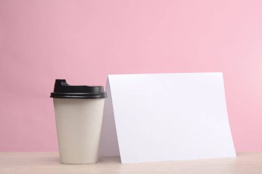 Boş beyaz kağıt takvimi olan kahve fincanı ya da pembe arka planda el ilanı modeli.