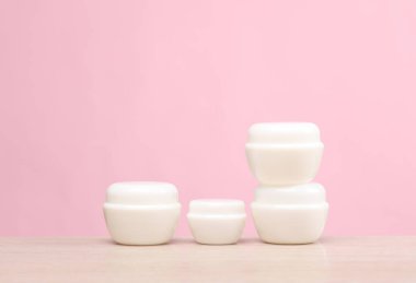 Masada beyaz krema kavanozları, pembe arka plan. Yaratıcı düzen. Tasarım şablonu. Güzellik modeli.