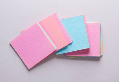 Gri arkaplan üzerine renkli not kağıtları yığını. Üst görünüm