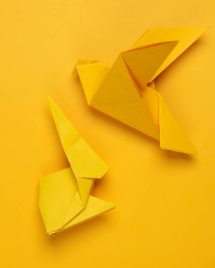 Sarı origami tavşanı ve sarı arka planda güvercin.