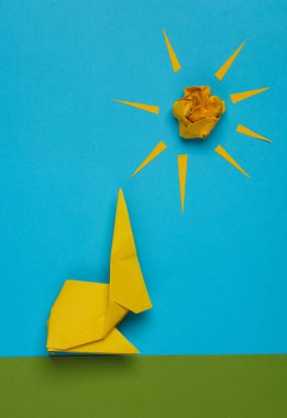 Sahne kağıttan yapılmış Origami tavşanı çimlerin üzerinde, gökyüzü ve güneş