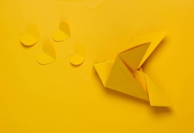 Sarı arka planda kalpleri olan Origami sarı güvercini. Barış, aşk konsepti