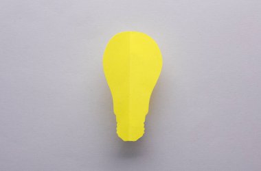 Gri arka planda kağıt kesiği ampulü. Yaratıcı fikir, aydınlatma