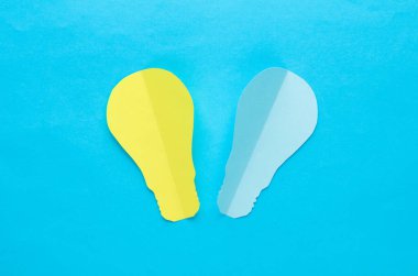 Mavi arka planda kağıt kesikli ampuller. Yaratıcı fikir, aydınlatma