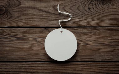 Yuvarlak beyaz fiyat etiketi ve ahşap bir masa üzerinde ip. Tasarım şablonu