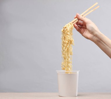 Gri arka planda hazır şehriyeli Çin yemek çubuğu tutan bir kadın. Yaratıcı model