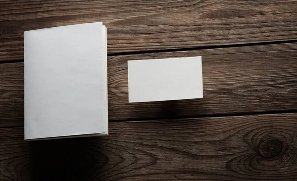 Book mockup with white cover and business cards on wooden table