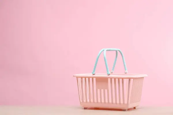 Plastic mini supermarket basket on a pink background. Sale concept