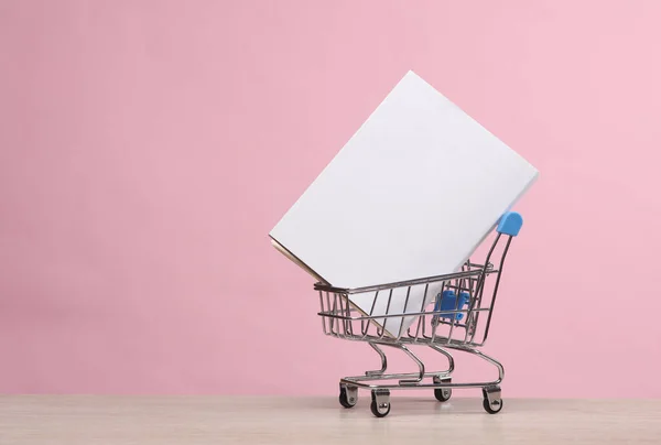 Mini supermarket cart with white cover book mockup on pink background