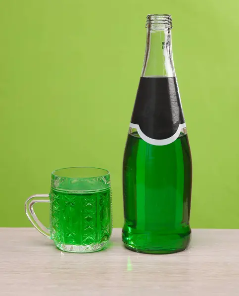 Bottle of green irish beer with glass on green background