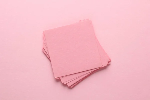 Stack of pink square memo sheet of papers on pink background. Top view