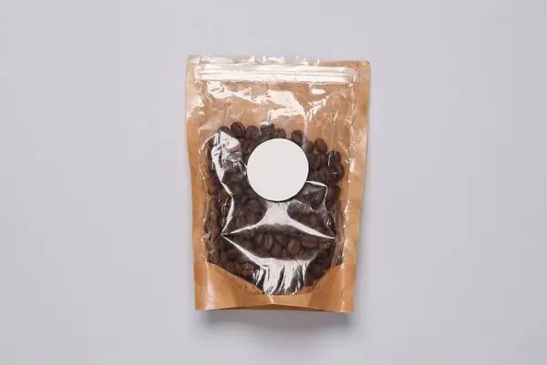 Package of coffee beans with a round label on a gray background
