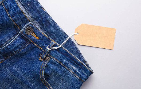 Blue jeans with a craft price tag on a string, gray background