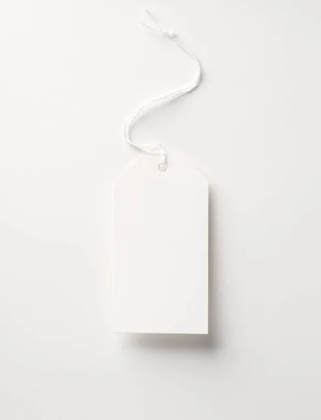 Empty white paper price tag with string on gray background. Template for design
