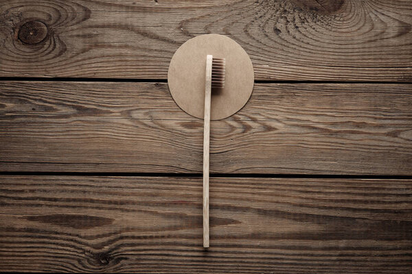 Wooden toothbrush on wooden background with circles. Eco concept. Top view.