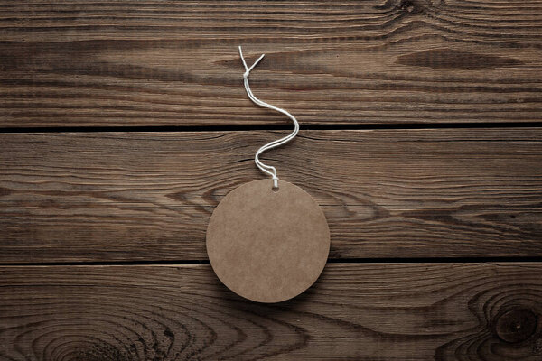 Empty round craft price tag with string on wooden background. Template for design