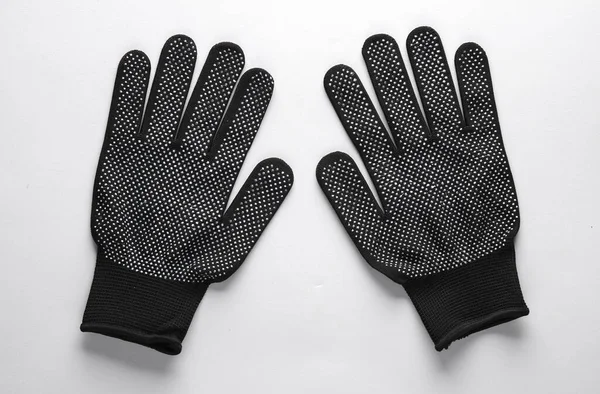 Black work gloves on a gray background. Top view