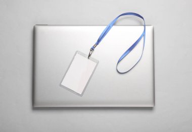 Laptop ve boş beyaz kimlik kartı gri arka planda. Personel kimlik kartı. Metin ve tasarım için boşluk.