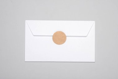 Gri arkaplanlı yuvarlak etiketli beyaz zarf