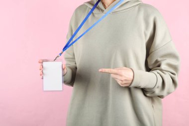 Pembe arka planda beyaz kimliği olan genç bir kadın.