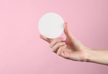 Kadın eli, yazı için beyaz boş bir daire tutar, pembe arkaplan