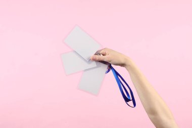 Pembe arkaplanda el ele tutuşan beyaz kimlik kartları.