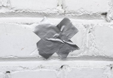 Metal yapıştırıcı bantla kaplı tuğla duvara yakın plan.