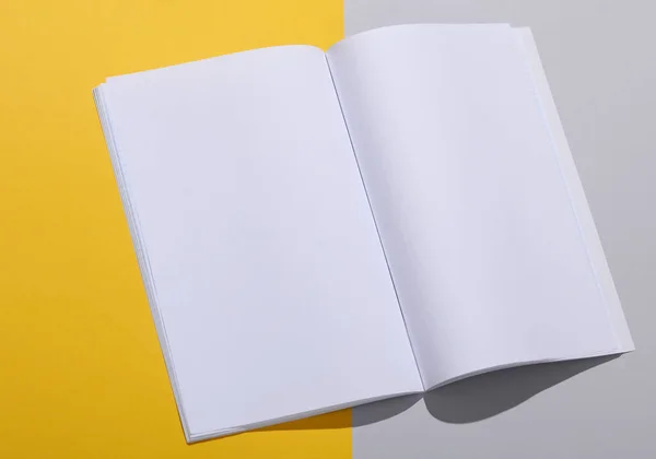 Mockup of open magazine with white open pages on a gray yellow background. Template for design