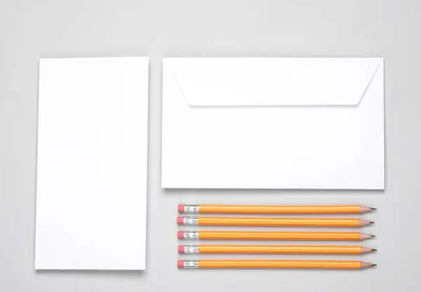 Creative layout white envelope with blank letter and pencils on gray background. Flat lay