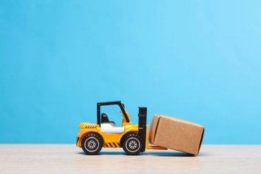 Mavi arka planda kutulu bir forklift minyatürü. Teslimat, ulaşım, depolama