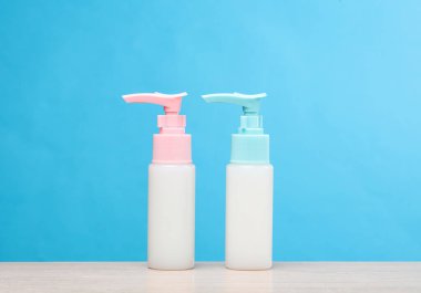 Masanın üzerinde iki şişe krem şanti var, mavi arkaplan.