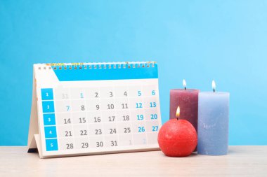 Masanın üzerinde yanan mumlar olan mavi arkaplan takvimi