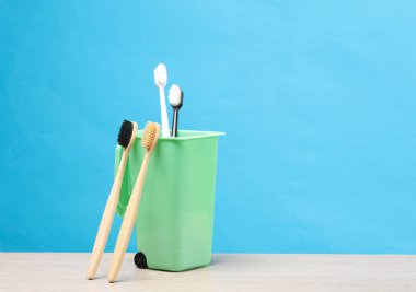 Beleş plastik. Masasında plastik diş fırçası ve ahşap diş fırçası olan bir vazo.