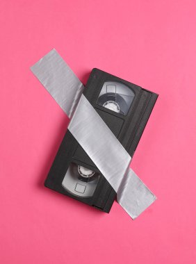 Retro video kaseti, pembe arka planda yapıştırıcı bantla sabitlenmiş. Kavramsal pop, çağdaş sanat, minimalist natüralist hayat