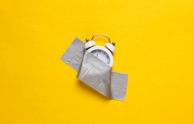 Alarm saati sarı arkaplanda yapıştırıcı bantla sabitlendi. Kavramsal pop, çağdaş sanat, minimalist natüralist hayat