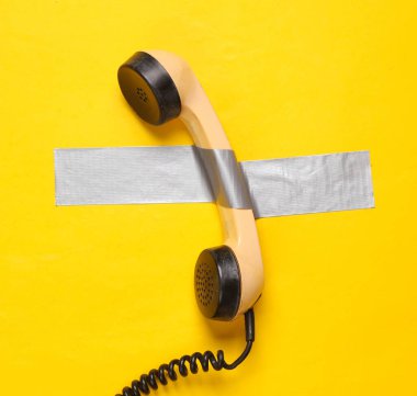 Retro telefon tüpü sarı arka planda yapıştırıcı bantla sabitlendi. Kavramsal pop, çağdaş sanat