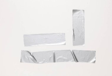 Beyaz bir duvarda farklı metalik yapıştırıcı şeritler var.