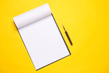 Sarı zemin üzerinde boş kağıt ve kalem olan bir pano. İş konsepti. Tasarım şablonu