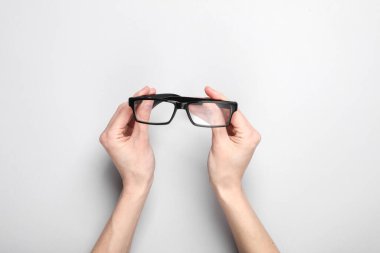 Kadınların elleri gri bir arka planda gözlük tutuyor. Vizyon düzeltmesi