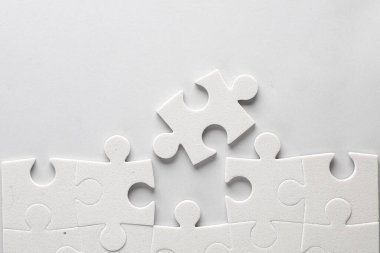 Gri arkaplanda beyaz yapboz parçaları.