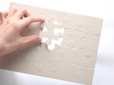 Kadın eli, gri arka planda beyaz bir yapboz oluşturur.