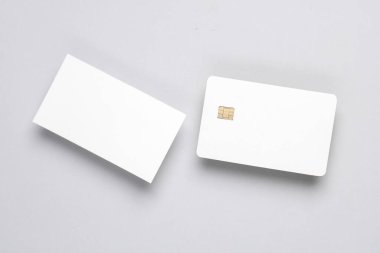 Gri arkaplanda çip ve kartvizit olan beyaz, boş bir banka kartı. Tasarım şablonu